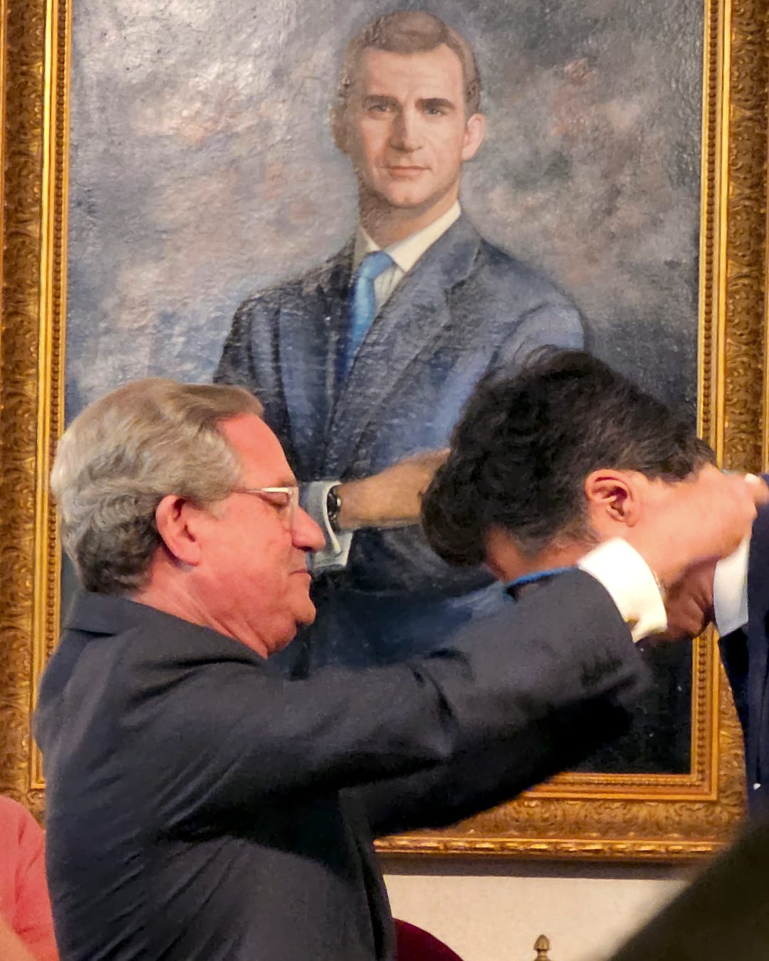 César Saldaña impone a Willy Pérez la medalla de académico, con el retrato de Felipe VI presidiendo la sala
